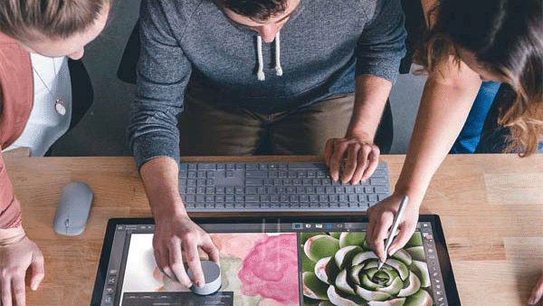Three individuals collaborating on one large monitor using interactive tools.